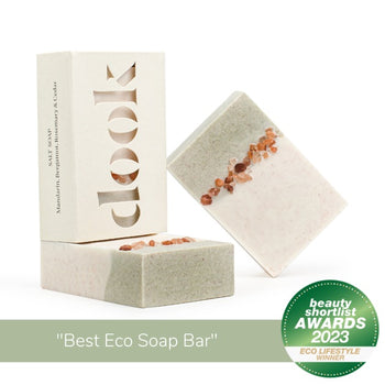 Three bars of soap, two unboxed with green and creamy-white colour split with a decorative line of Himalayan rock salt and one in a box in a composition on the white background and eco lifestyle winner beauty shortlist awards 2023 badge and title "best eco soap bar".
