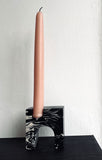 A single pink tall candle in a stone marbled black and white candle holder.