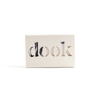 A bar of soap in the creamy-white recycled paper box with the dook logo on the white background. 