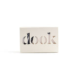 A bar of soap in the creamy-white recycled paper box with the dook logo on the white background. 