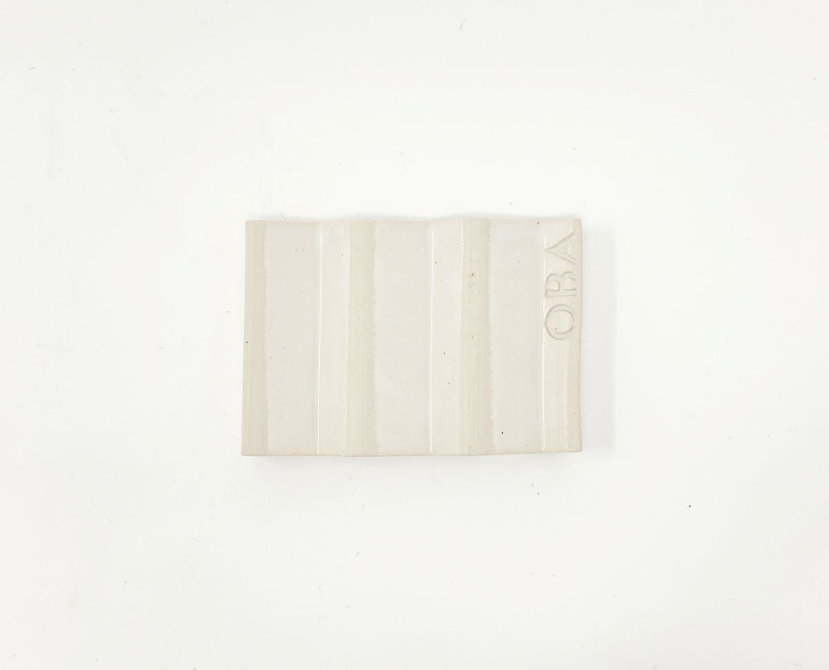 White zig-zag shaped OBA Ceramic soap dish on the white background - underneath view.