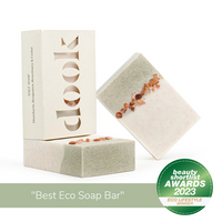 Three bars of soap, two unboxed with green and creamy-white colour split with a decorative line of Himalayan rock salt and one in a box in a composition on the white background and eco lifestyle winner beauty shortlist awards 2023 badge and title "best eco soap bar".