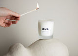 Hand holding a burning match above the dook candle. Candle stands on the sculpture on the light beige background. 