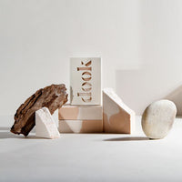 Artistic setup of a handmade soap bars arranged with piece of cedar wood and a stone on the white background.