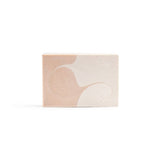 A single handmade bar soap presenting its orange and creamy white pattern suggesting a sea wave. 