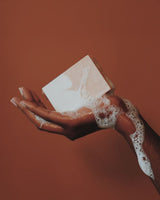 A bar soap lathered on human hand on the copper colour background. 