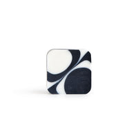 A square-shaped handmade bar of soap with white and black irregular round pattern on the white background. 