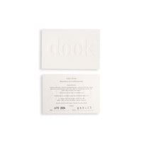 Two recycled paper cards, one with embossed logo and one with the description of the soap on the white background.