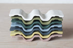 Stack of porcelain wavy tops of a soap dish exposing all available colours.