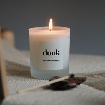Dook candle being lit, standing in the natural piece of fabric in a cosy room.