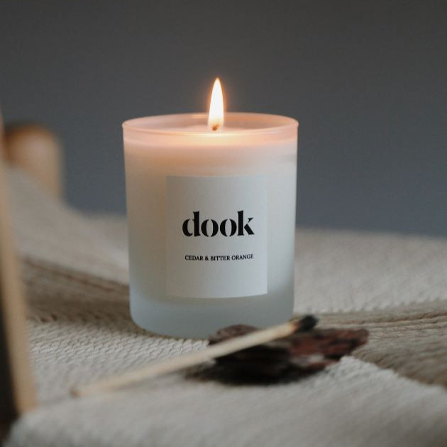 Dook candle being lit, standing in the natural piece of fabric in a cosy room.
