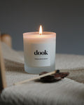 Dook candle being lit, standing in the natural piece of fabric in a cosy room.
