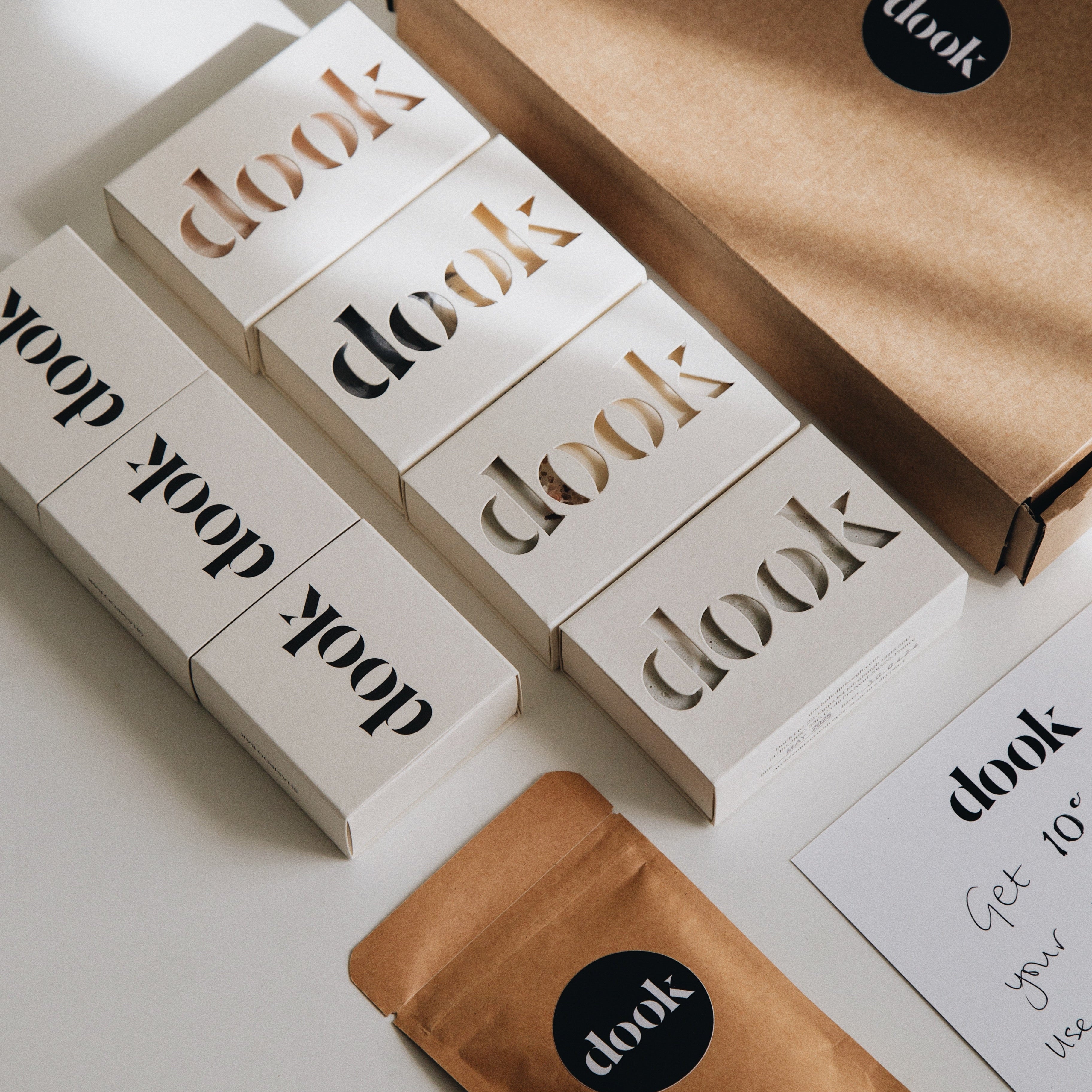 Subscription box of four soaps, three shampoo bars, a product sample and a discount card layered down on the white background next to a brown box.