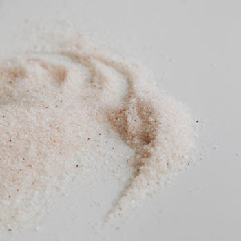 Handblended himalayan salt with darker pink grains spread over the white surface.