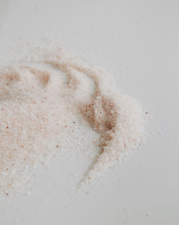 Handblended himalayan salt with darker pink grains spread over the white surface.