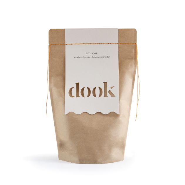 Brown eco bag with mandarin scented bath salts. White label with dook logo sewed with orange thread. On the white bacground.