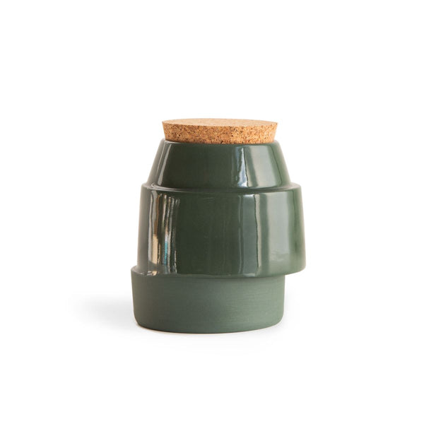 Green, off-centre handmade ceramic jar for bath salts with a cork lid on the white background.