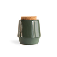 Green, handmade ceramic jar for bath salts with a cork lid on the white background.