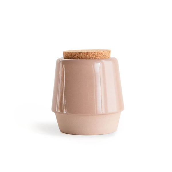 Dusty pink, handmade ceramic jar with cork lid on the white background.