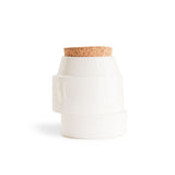 White, off-centre handmade ceramic jar for bath salts with a cork lid on the white background.