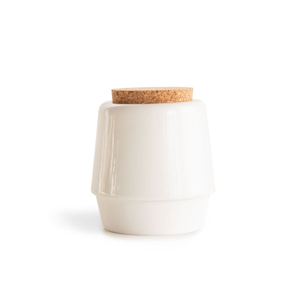 White, handmade ceramic jar for bath salts with a cork lid on the white background.