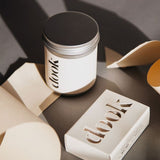 Dook's bath salts in tin and a bar of soap arranged with bits of folded white paper creating an artistic composition.