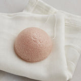 A pink konjac sponge on the muslin white cloth.