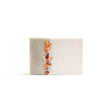 A handmade bar of soap with line of Himalayan salt rocks splitting light green left side from creamy-white right side on the white background.