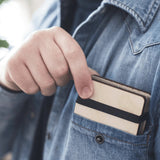 A person wearing a denim shirt has a mini flower press with a pink and purple floral design on it placed in their front pocket.