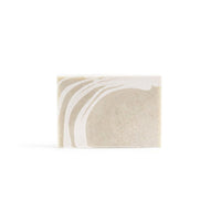 A clay green handmade patterned soap with a pattern of creamy-white lines in the top left corner.