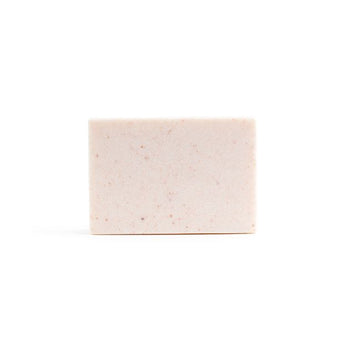A bare, light pink handmade bar of soap on the white background.