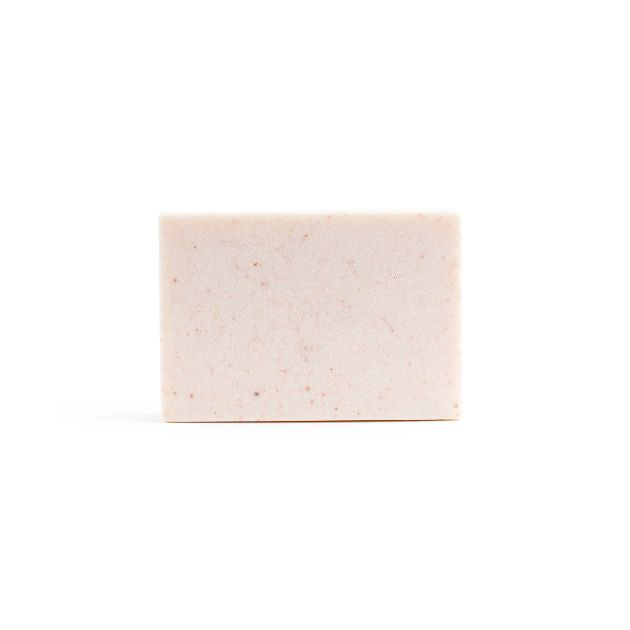A bare, light pink handmade bar of soap on the white background.