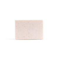 A bare, light pink handmade bar of soap on the white background.