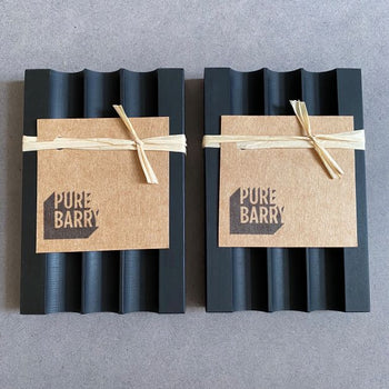 Two black 'Pure Barry' soap dishes next to one another.