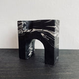 Stone candle holder marbled black and white for a single tall candle placed on a shelf.
