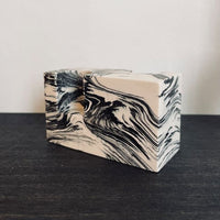 Marbled black and white stone candle holder on a shelf.