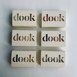 Six boxed dook soap lying flat in two columns of three soaps, exposing the beauty of recycled paper packaging and the logo.