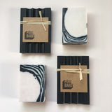 A 'chessboard' made of two black 'Pure Barry' soap dishes and two black and white patterned handmade Rosemary soap.