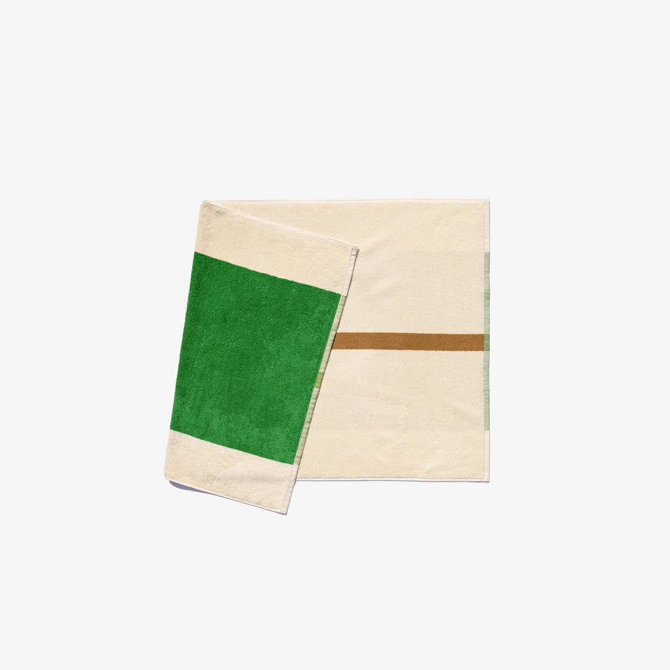 A folded bath mat with green and chestnut color blocks, likely made of cotton, on a white background.