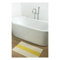 Bath mat with yellow stripe in front of a white bathtub