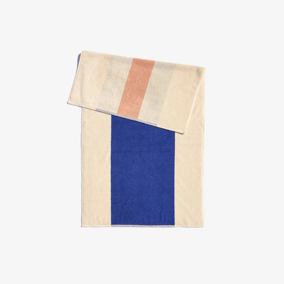 A folded bath towel with a block design featuring royal blue and peach colors, with a thin cream stripe in the center.