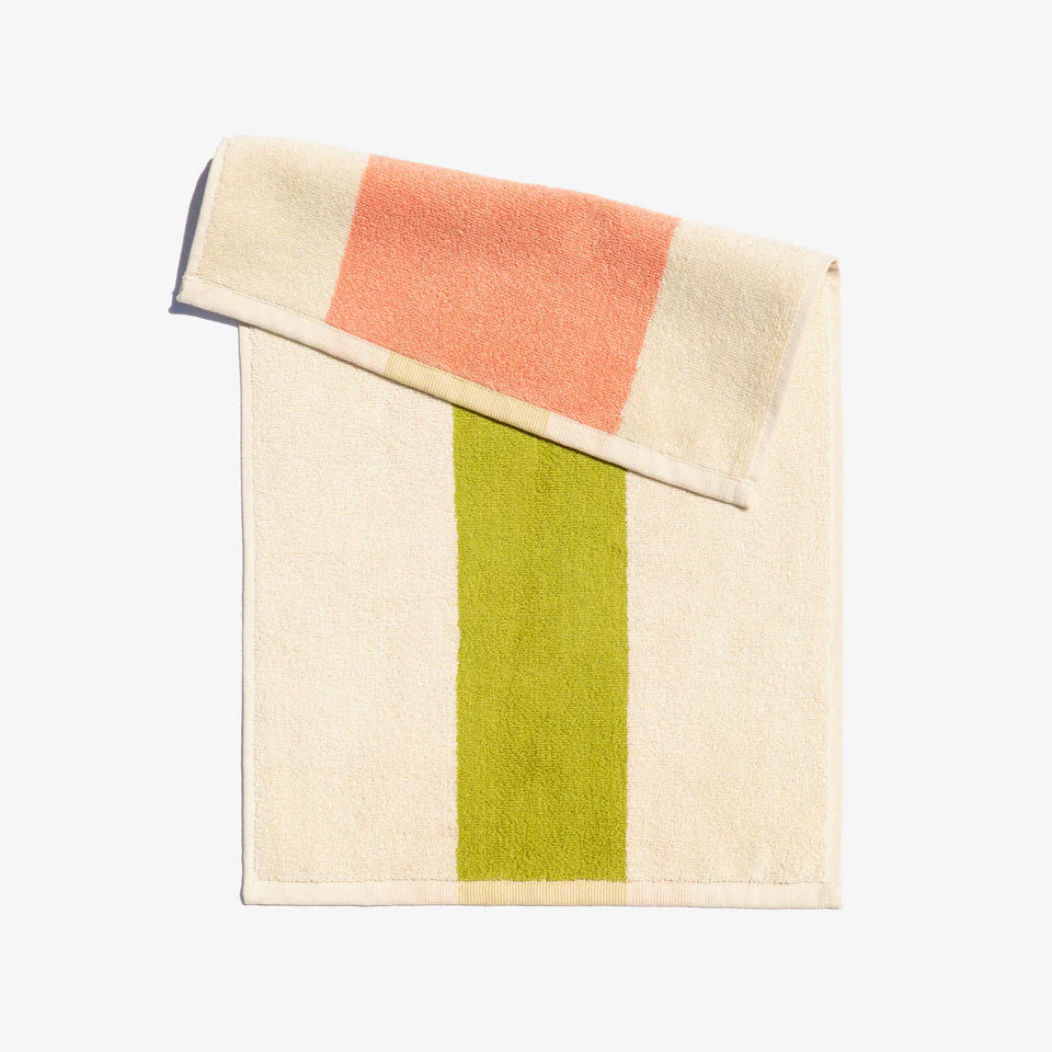 A folded face towel with peach and lime green horizontal stripes on a light background, with a loop for hanging.
