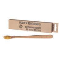 Wooden toothbrush next to its packaging on the white background.